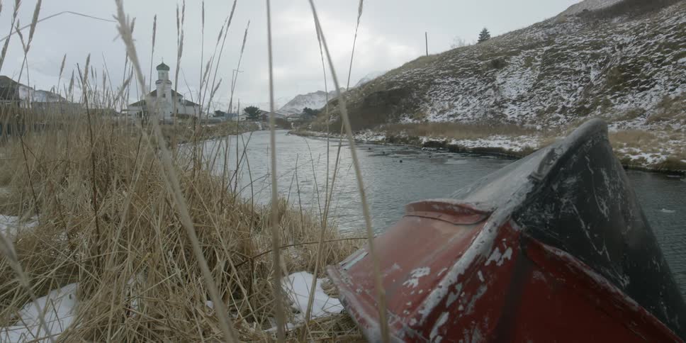 A boat sits overturned beside a stream
