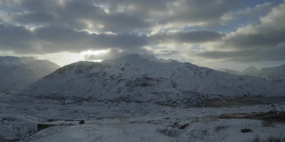 Clouds passing over snowy hills at sunset