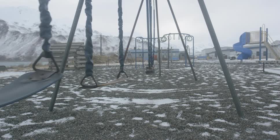Snow falls around a playground