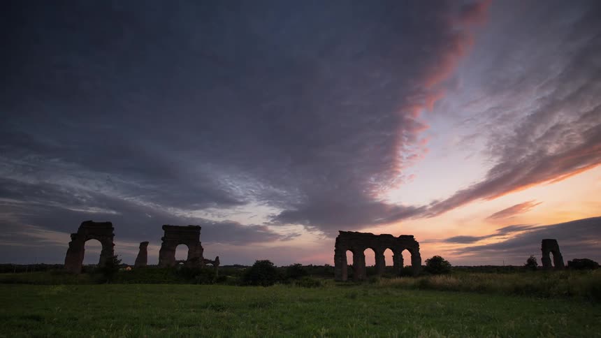 Past the green field are broken stone monuments