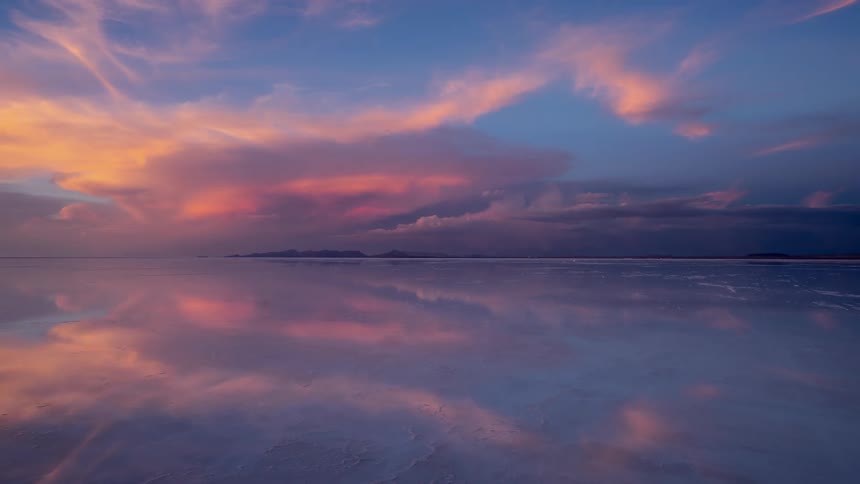Clouds float over a calm lake at sunset