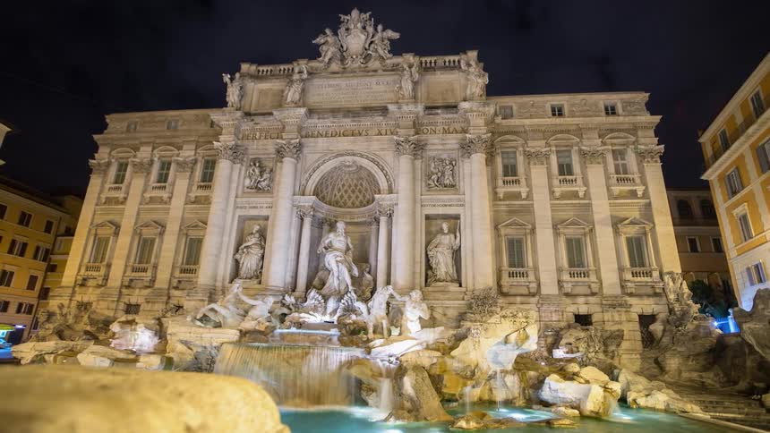 Lights illuminate a city fountain at night