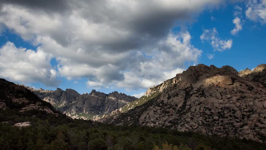 Clouds are moving across mountains during the day