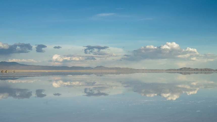 Clouds pass above a lake as the sun shines