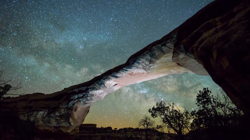 Stars pass over a rock archway