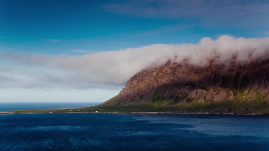 White clouds roll over the ocean side hill top
