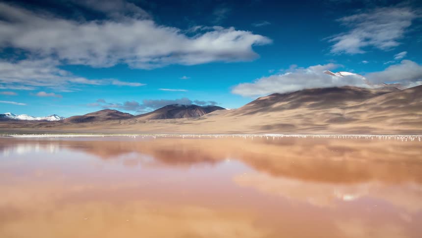 Clouds pass above a lake and a mountain