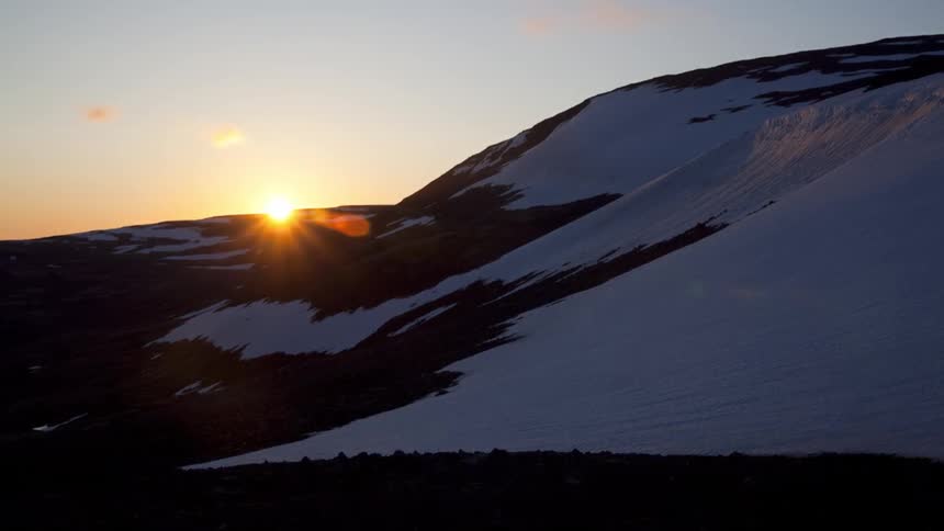 The sun sets behind a mountain