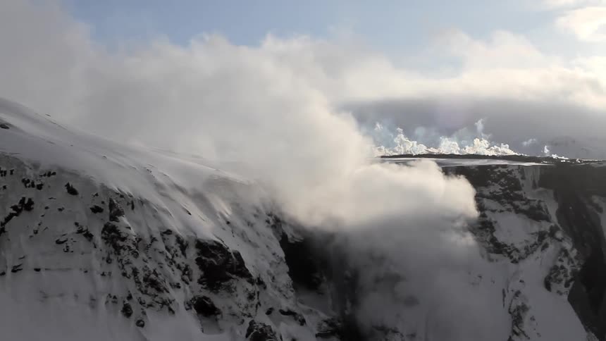 Clouds and fog roll over snow capped mountains