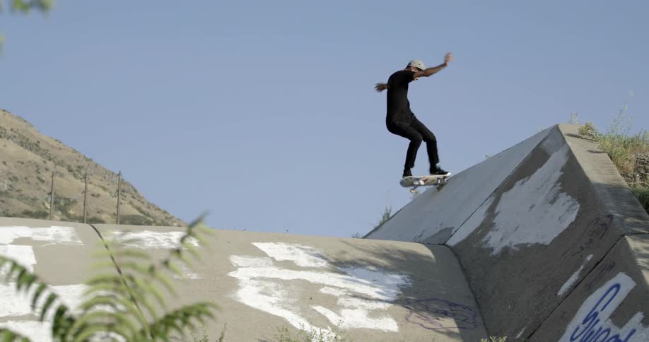 A skateboarder riding up and down an outdoor ramp