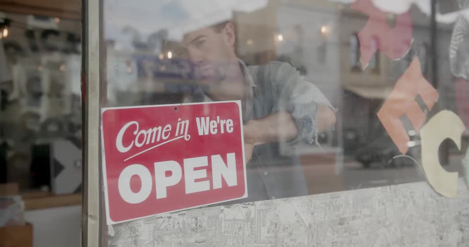 An employee flips a store sign to open