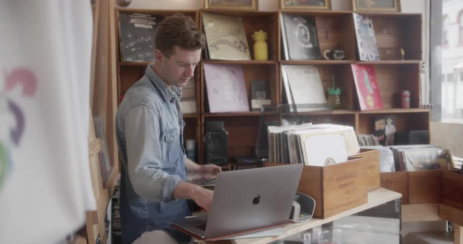 A record store worker types on a laptop