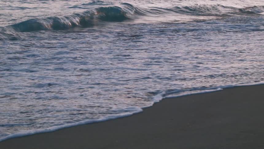 Ocean waves rolling onto beach in the evening
