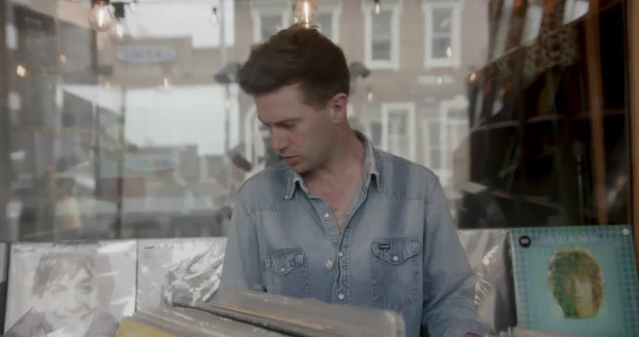 A man working in a record store picks up an album