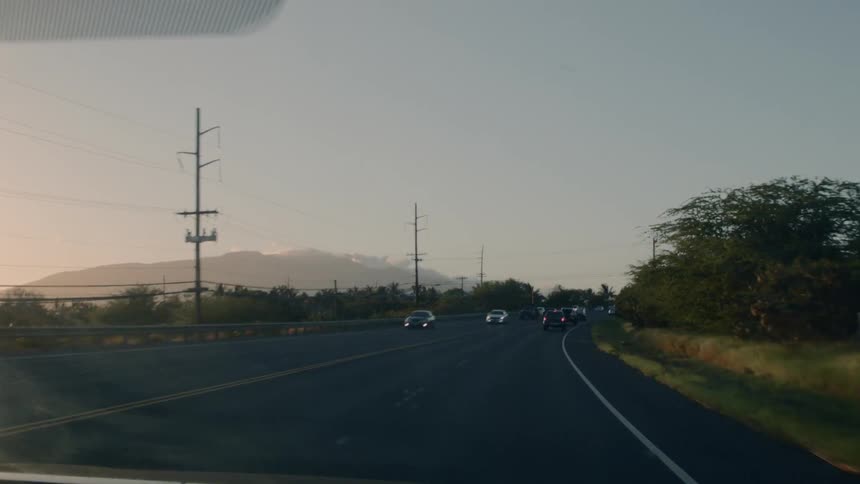 Cars drive on a road at sunset