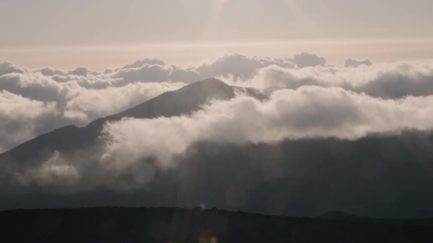 Clouds float over mountains at sunset