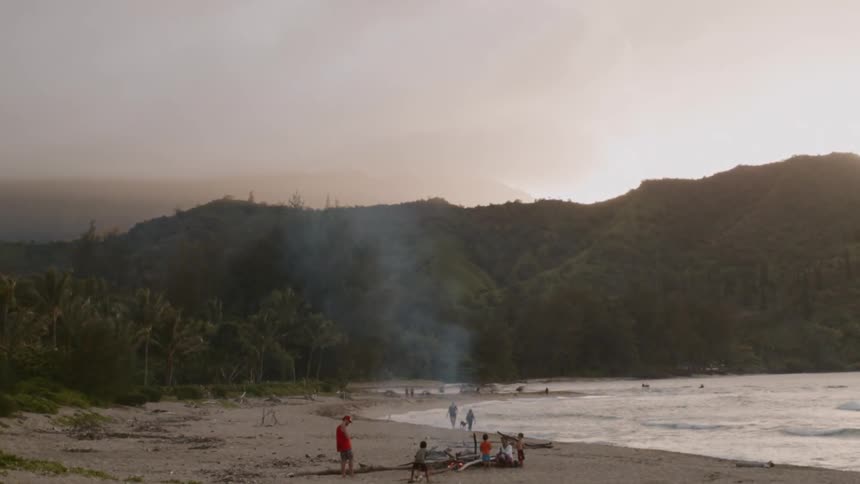 People are enjoying the beach at dusk on a cloudy day