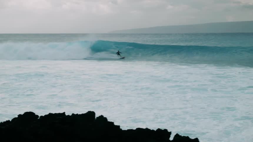 Surfer riding a wave on a cloudy day
