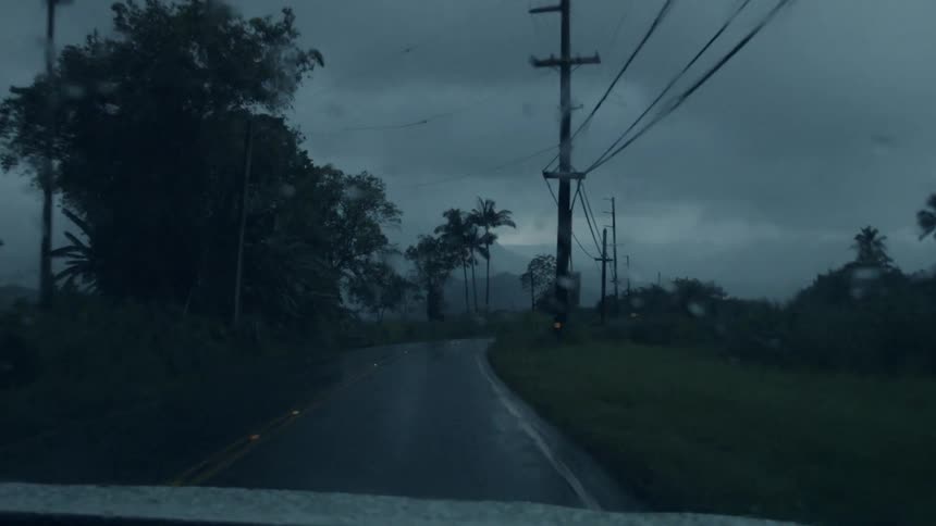 Vehicles travel down a wet and rainy road