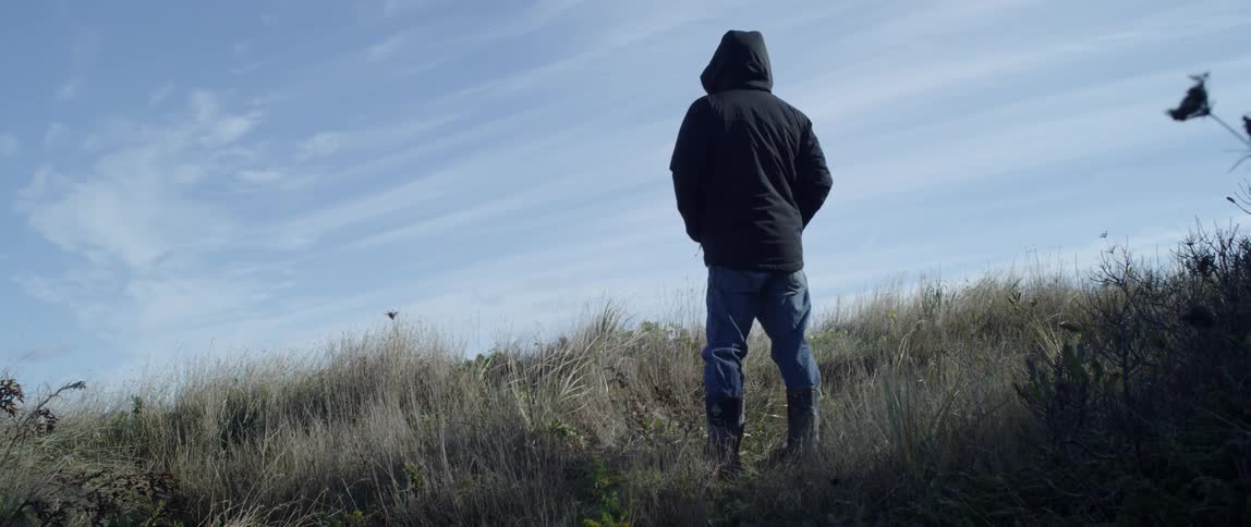 A man in a jacket stands in a field