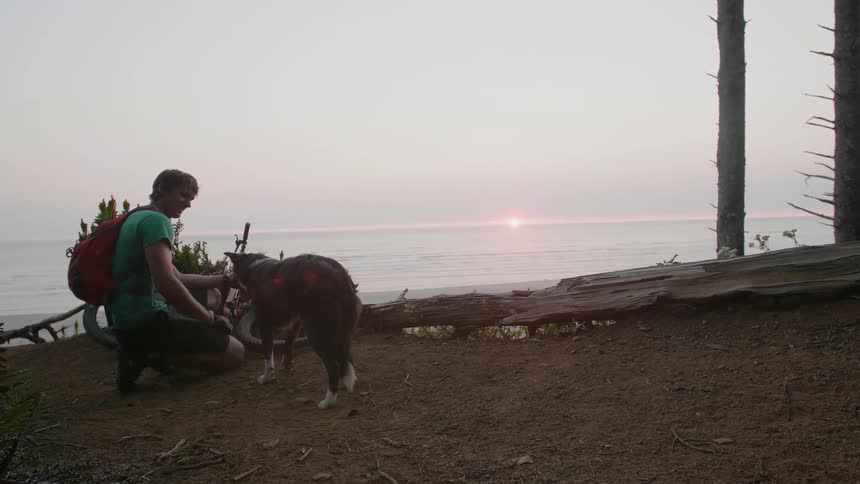 A man is kneeling down petting his dog