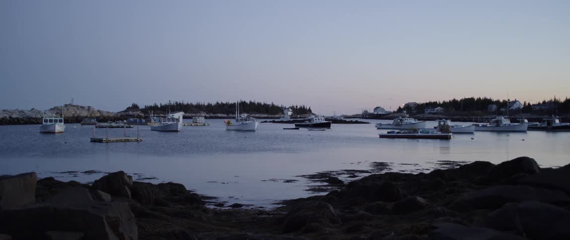 Boats float on a lake at sunset