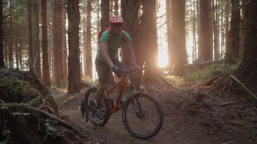 Man rides bike on bumpy path through forest