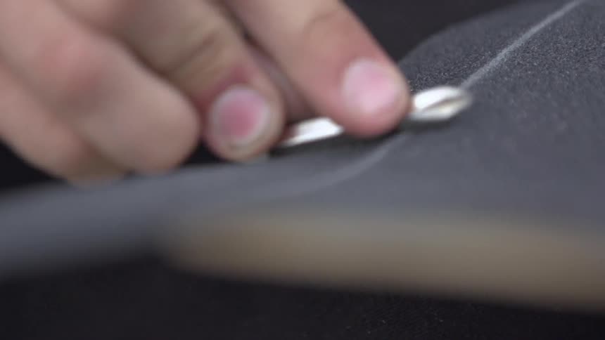 A person rubbing fabric with a metal object