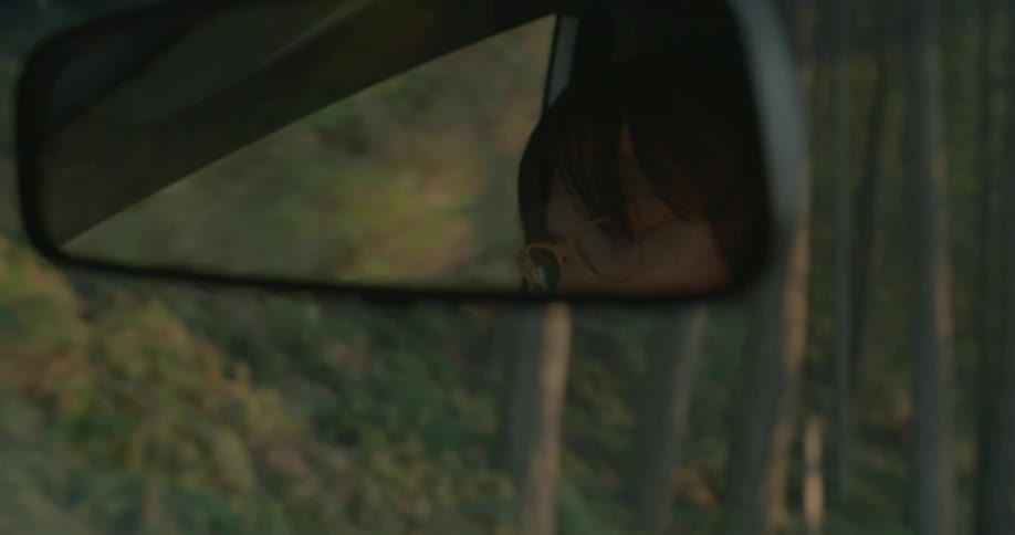 A woman's reflection is seen in a rearview mirror while she drives