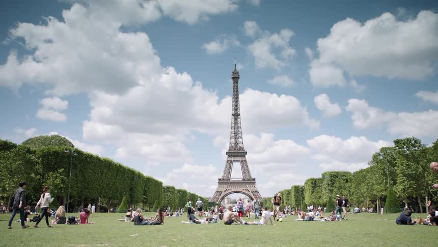 People sit in a field near the eiffel tower