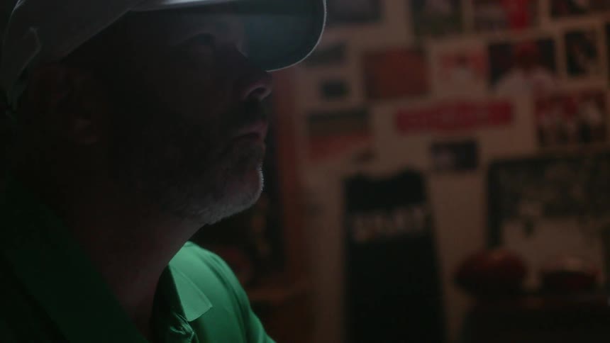 A man in a hat is writing something down and then looks up