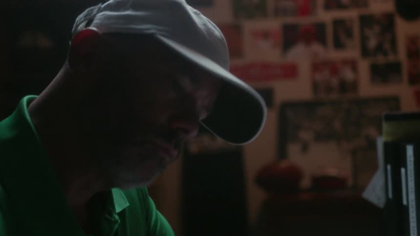 A man turns his head sideways as he looks at items in a room