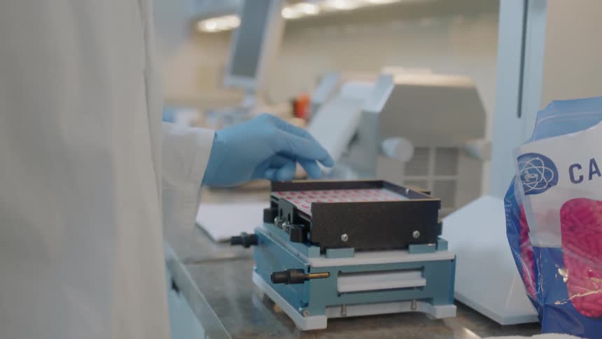 A medical technician packs pills using machinery