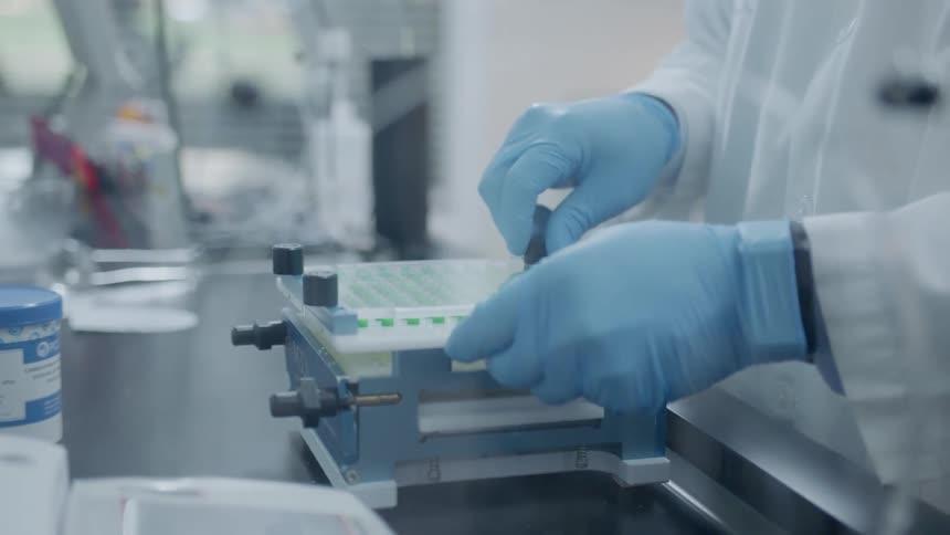 A worker in a lab takes the cover off a pill tray