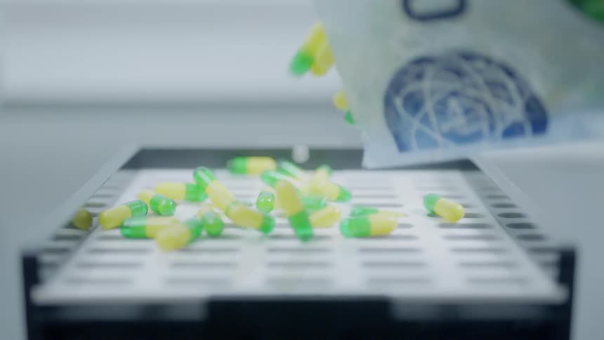 Pills are poured into a container in a laboratory