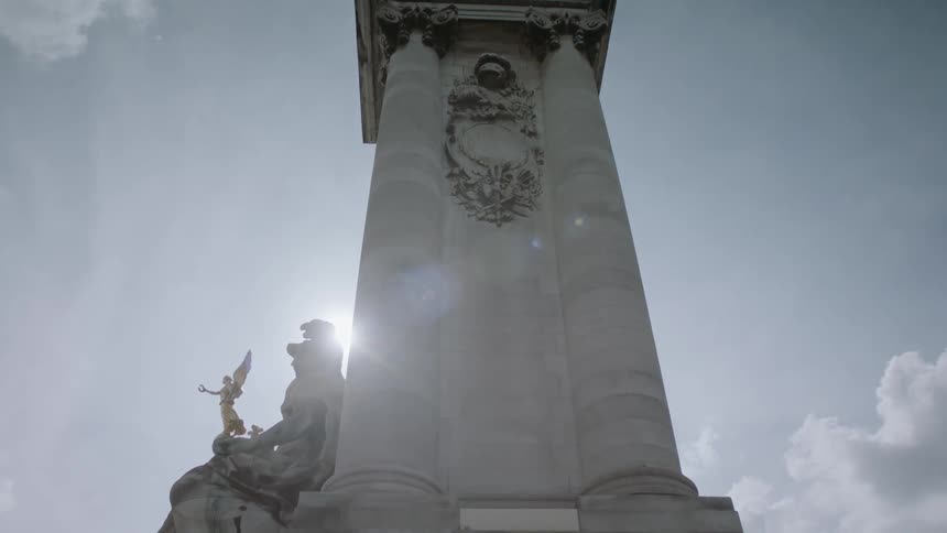 The sun is shining down on a monument with statues during the day
