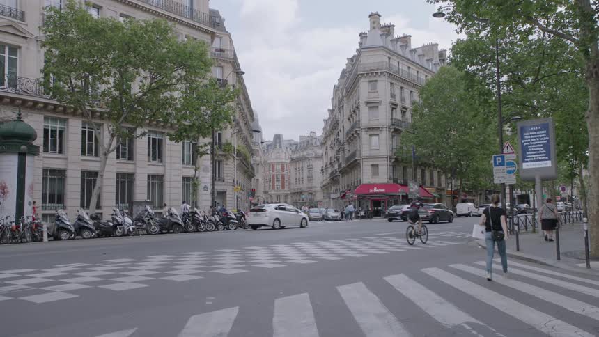 People and cars travel through a city intersection