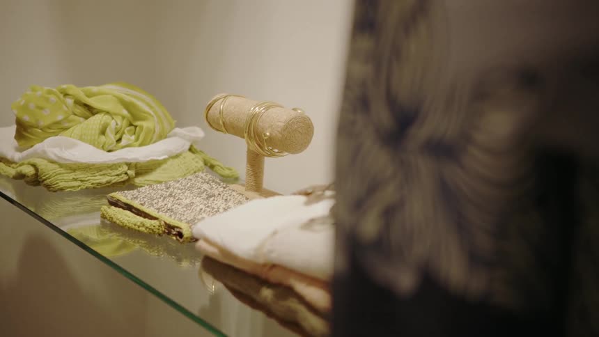 Jewelry and clothing are resting on a shelf in a display case