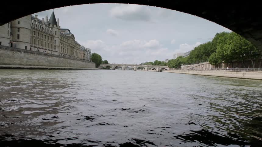 River of water flowing under bridges near buildings and trees