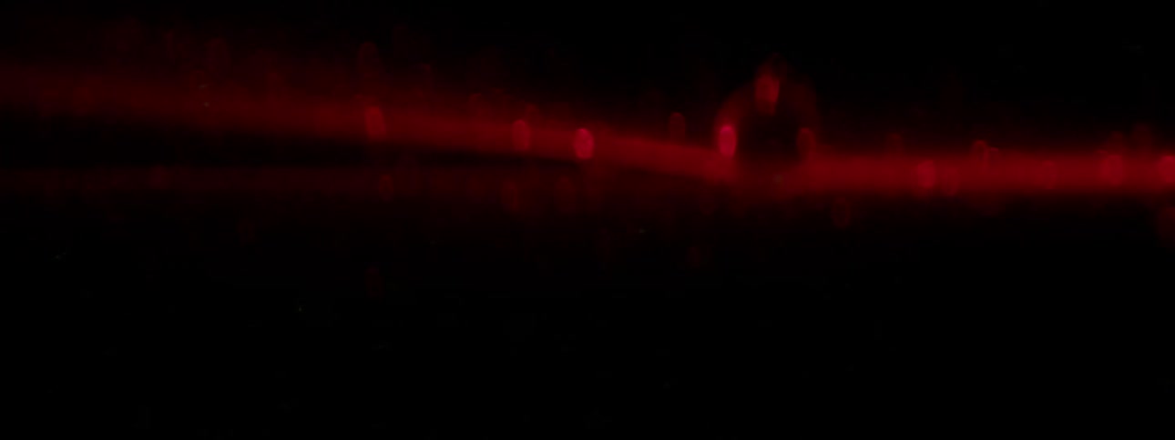 A laser shines through darkness