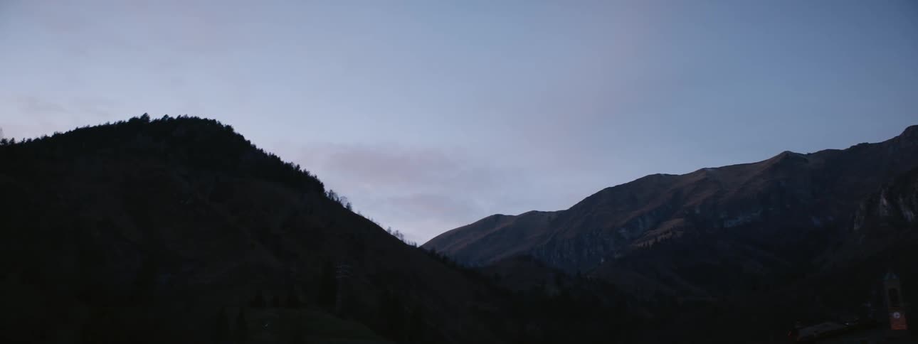 Clouds float over mountains at sunset