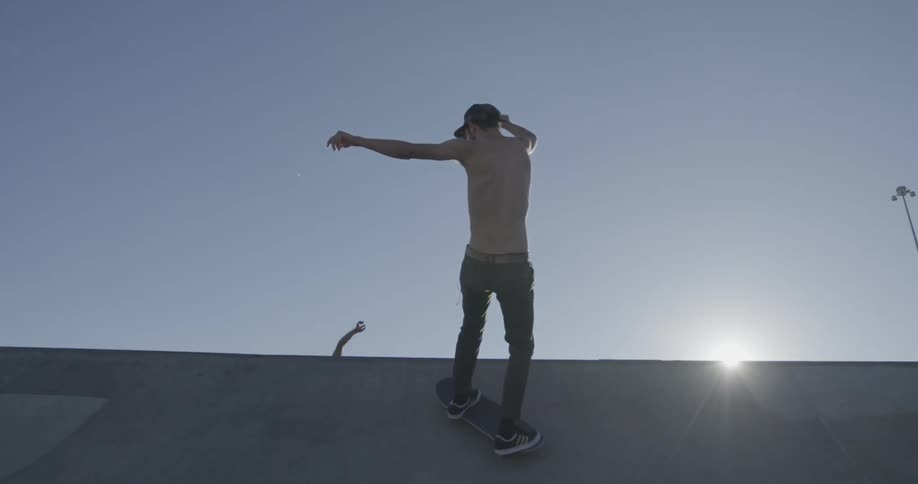 Two young men riding their skateboards to the top of a half pipe and one going back down it