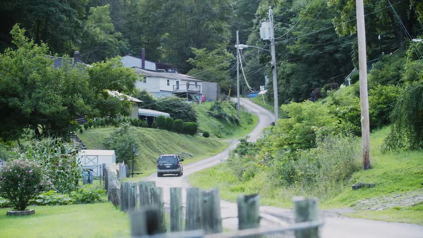A truck drives up a rural road