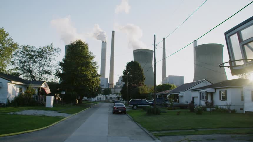 Smoke rising from an industrial area at the end of a city street