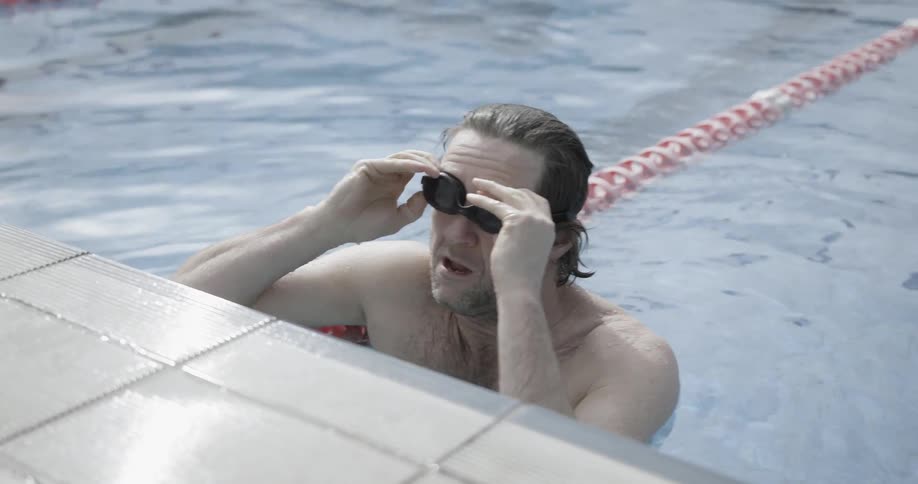 A man puts on goggles and swims in a pool