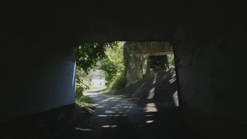 A covered bridge is casting shadows on a country road during the day
