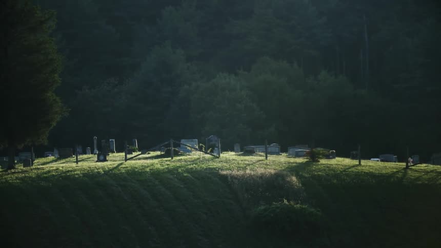 Shadows are lingering on a hillside and cemetery