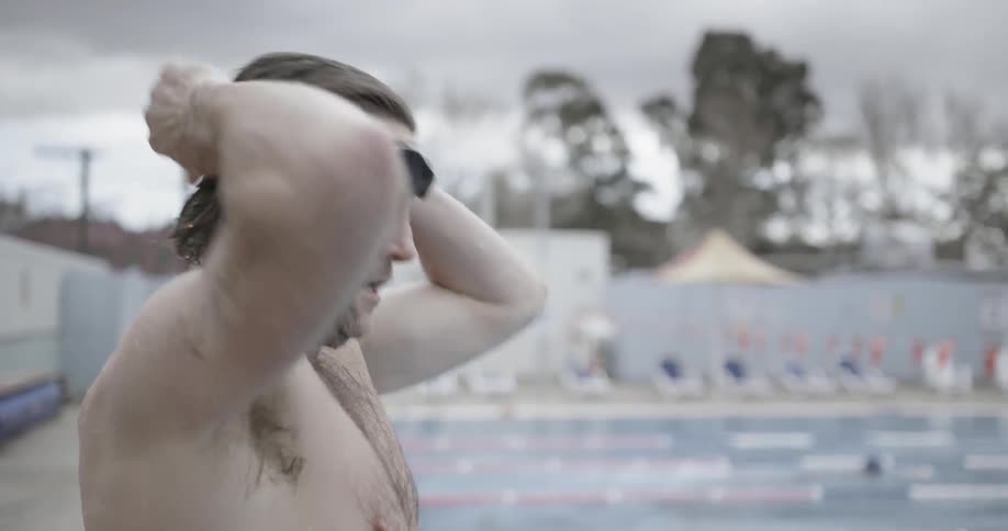 A man is preparing to dive into a swimming pool during the day