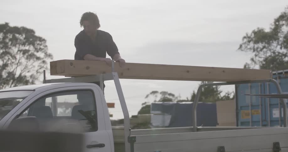 A forklift is lowering a large piece of wood on the back of a truck