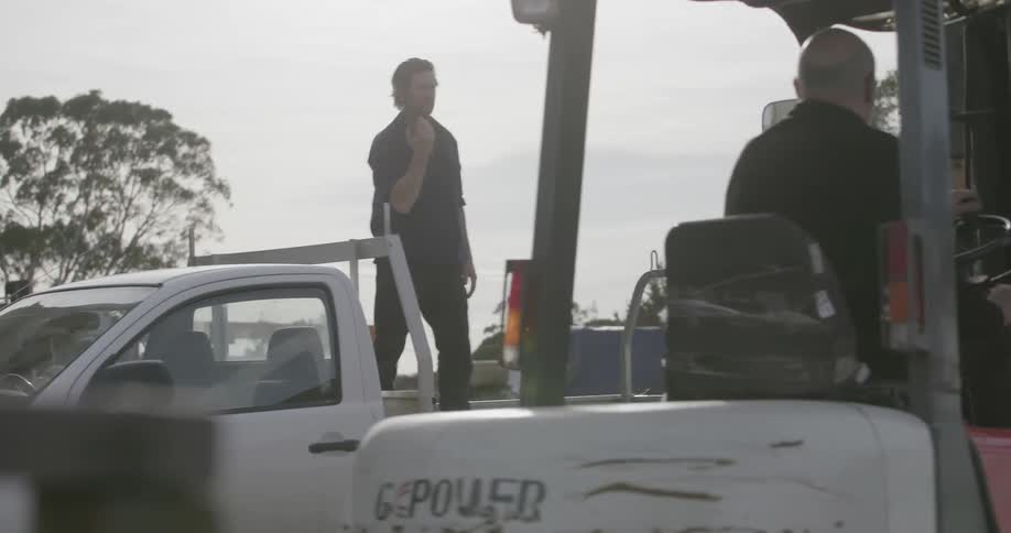 A man directs a forklift to his truck